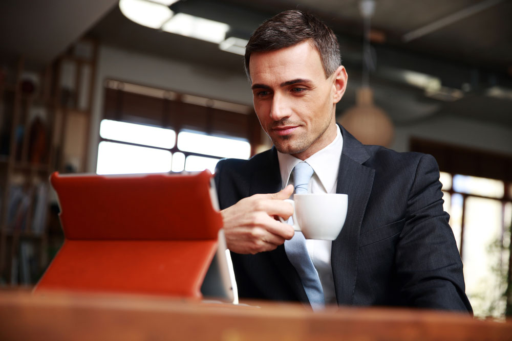 Businessman drinking coffee and reading news in cafe Businessman drinking coffee and reading news in cafe