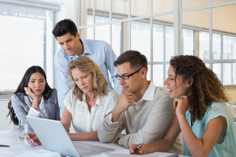 Casual business team having a meeting using laptop in the office