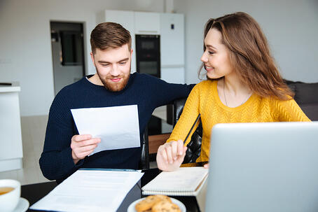 Happy young couple calculating bills at home 1