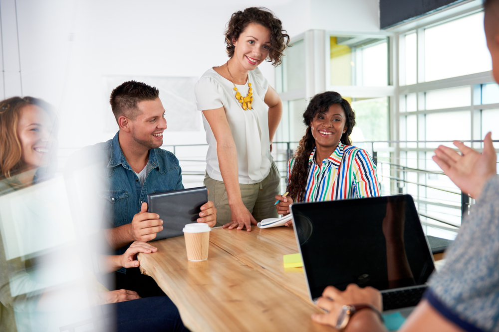 Multi ethnic group of succesful creative business people using a laptop during candid meeting Multi ethnic group of succesful creative business people using a laptop during candid meeting
