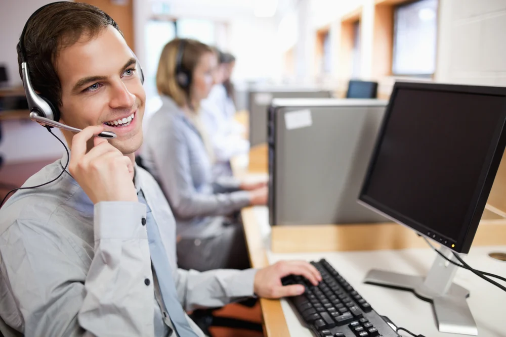Smiling assistant using a headset in a call center Smiling assistant using a headset in a call center