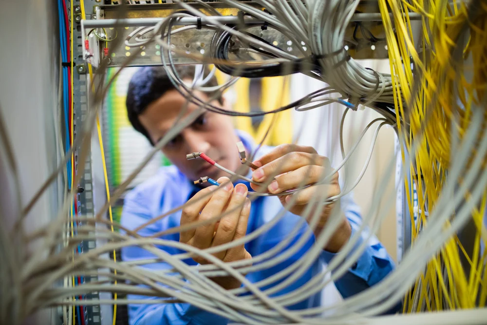 Attentive technician fixing cable in server room